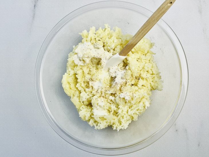 Creme de leite, sal e pimenta-do-reino adicionados a tigela com purê.