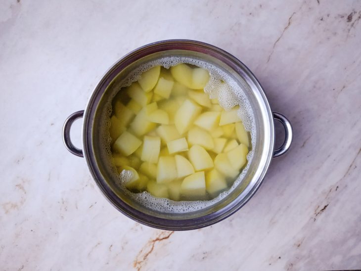 Batatas sendo cozidas em panela com água fervente e sal.