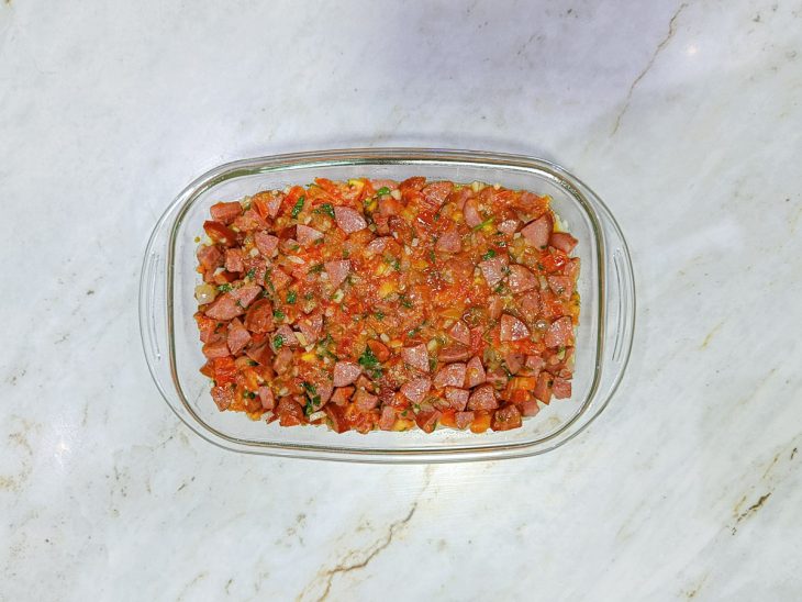 Camada de purê sendo espalhada na travessa, seguida pelo recheio.