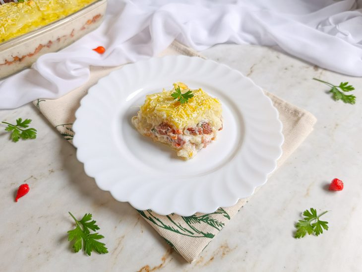 Escondidinho assado, dourado, sendo servido no prato.