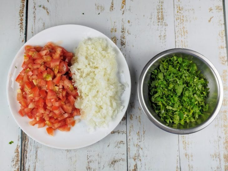 Tomate, cebola e coentro picados e reservados em recipientes.