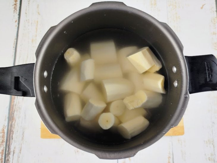 Mandiocas colocadas em uma panela de pressão com água.