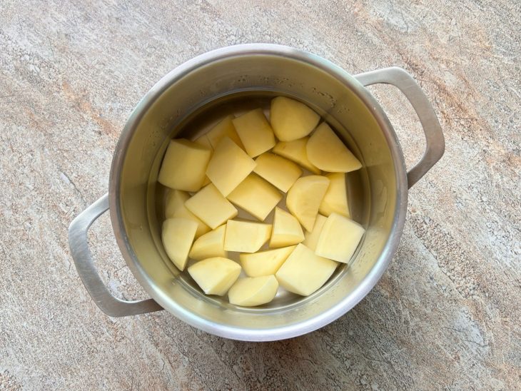 Numa panela, a batata cortada em cubos.