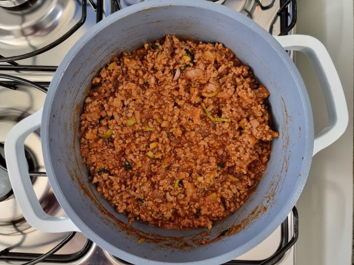 Panela com carne moída misturada com molho de tomate e temperos.