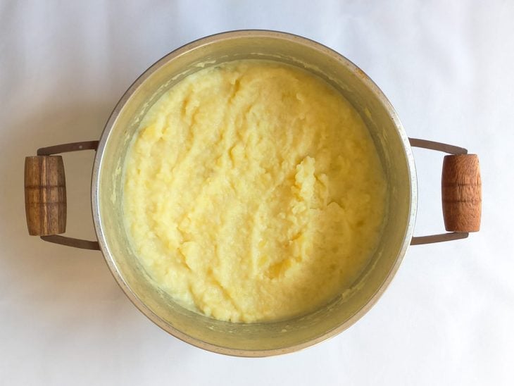 Batata amassada, leite e temperos adicionados na panela com cebola e manteiga.