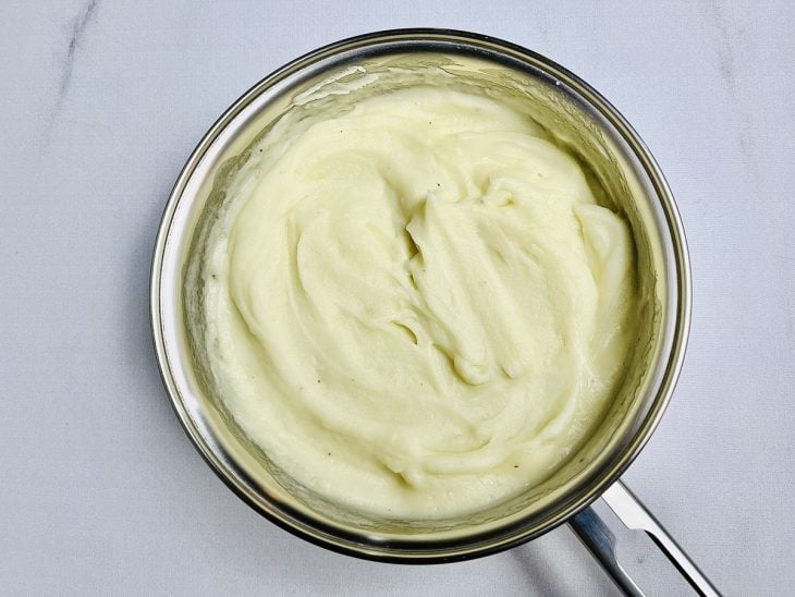 Batatas amassadas e leite adicionados e incorporados na panela.