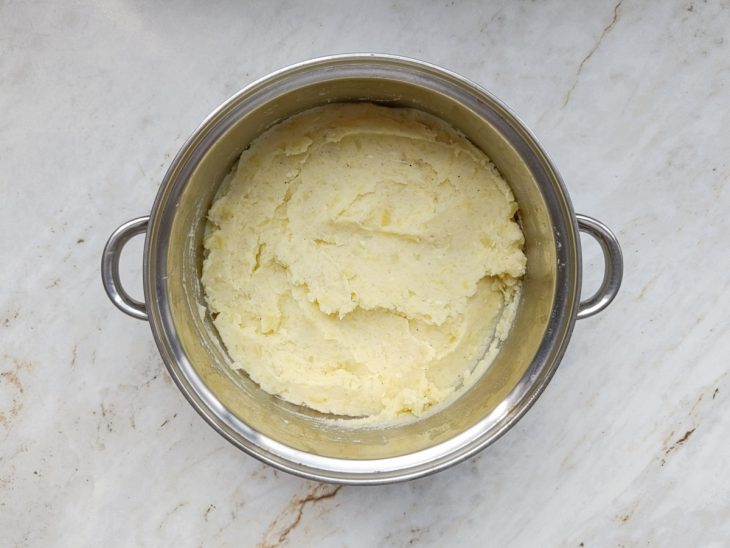 Manteiga, queijo parmesão, leite e temperos adicionados na panela.