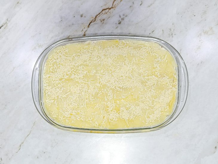 Camada de purê, mussarela e queijo parmesão adicionados no refratário.