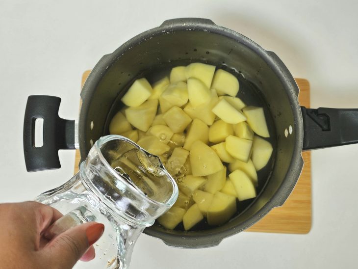Numa panela de pressão, as batatas com água para cozinhar.