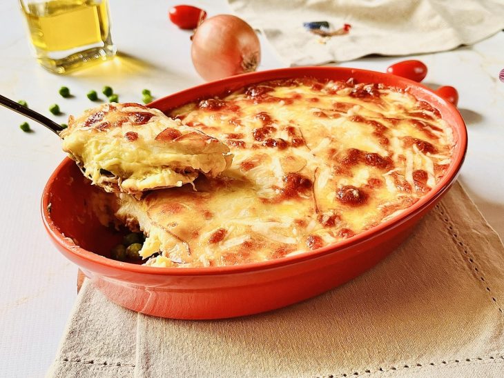 Escondidinho de frango com mandioquinha pronto para consumo e uma porção dele sobre um garfo.