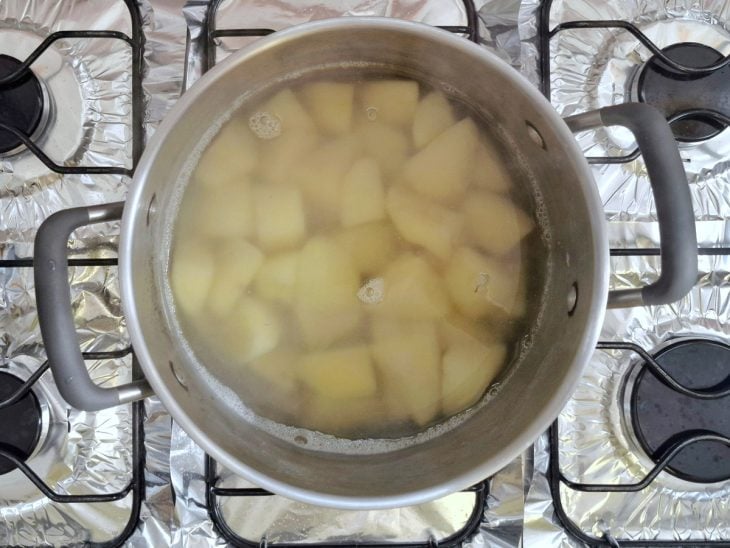 Batatas cortadas em uma panela com água e sal.