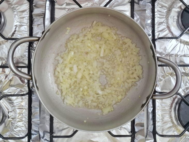 Cebola refogada com sal em uma panela com margarina.