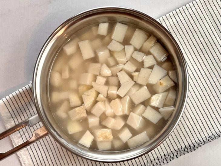 Panela com inhame cortado em cubos cobertos por água.