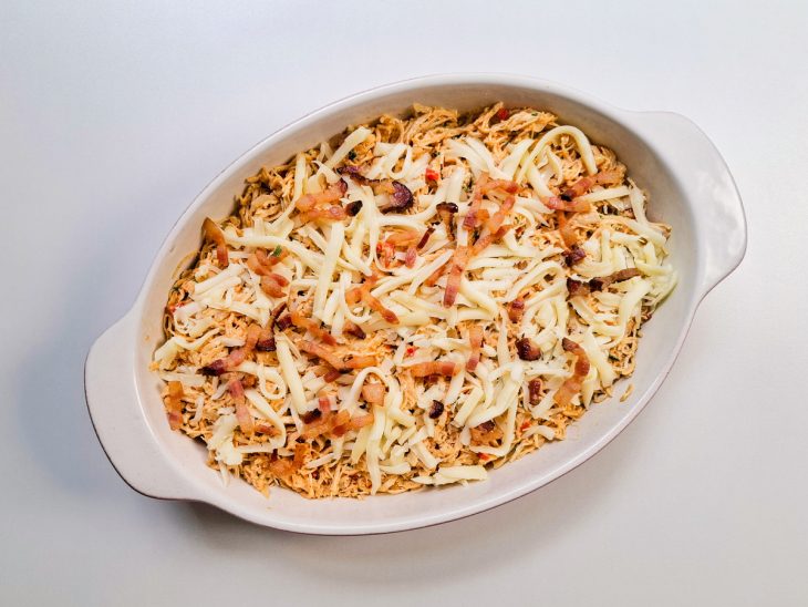 Na travessa, uma camada de frango com o bacon e queijo.