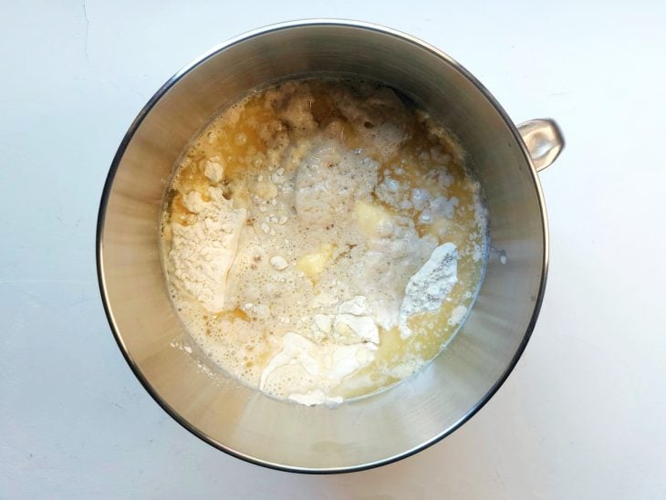 Um recipiente contendo a mistura de açúcar, fermento, manteiga, leite morno, farinha e sal.