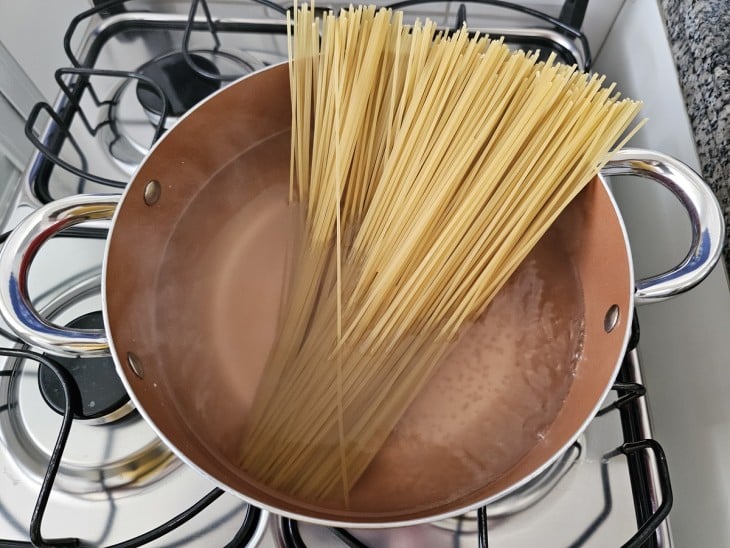 Uma panela com água e macarrão cru.