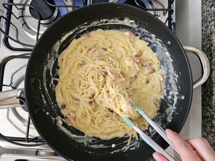 Uma frigideira com bacon, macarrão cozido e a mistura de ovos e queijo.