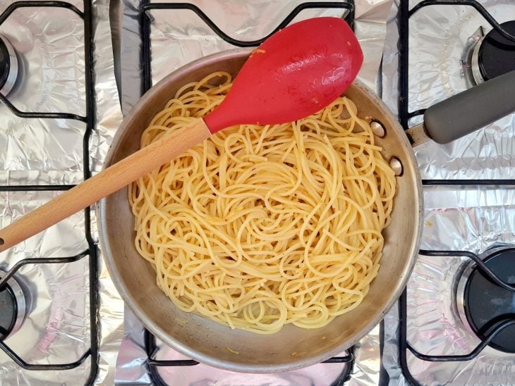 Macarrão escorrido e uma concha da água seu cozimento adicionados a frigideira.