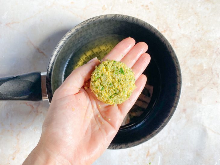 Falafel modelado ainda cru e panela com óleo ao fundo.