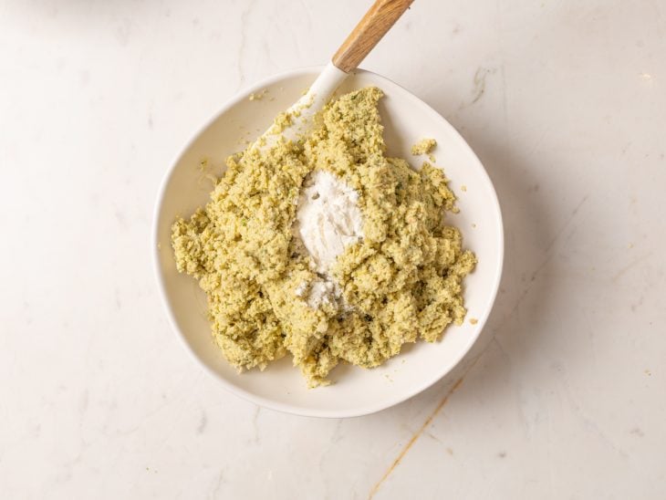 Massa de falafel, farinha, bicarbonato de sódio e azeite em uma tigela redonda.