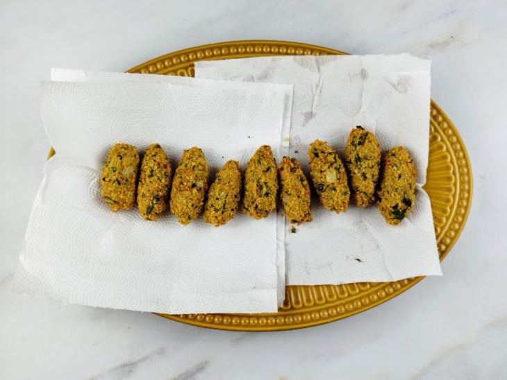 Bolinhos fritos e acomodados sobre o mesmo prato forrado por papel toalha.