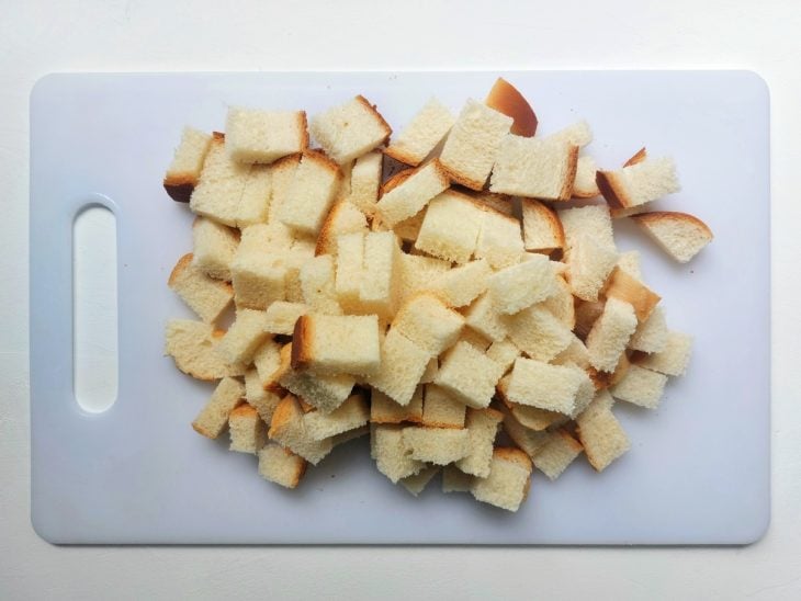 Uma tábua contendo um pão de forma cortado em pedaços.