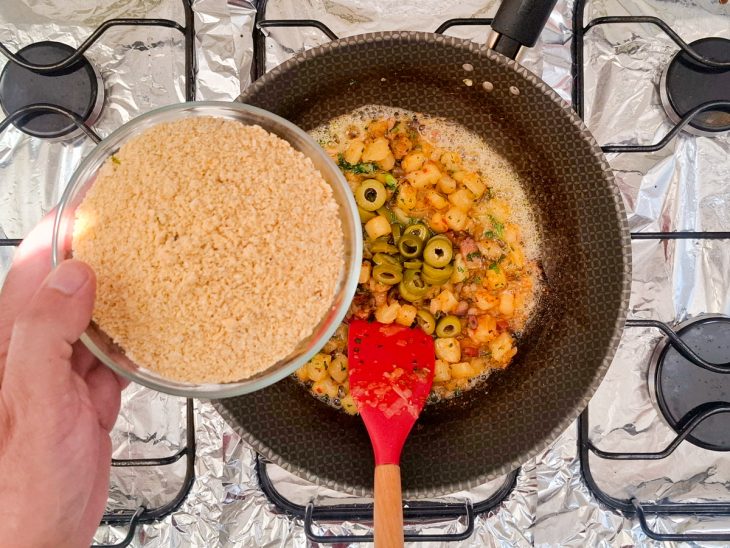 Azeitonas e cheiro-verde sendo adicionados ao preparo.