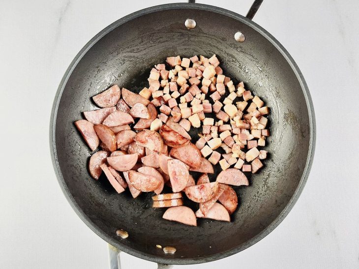 Bacon e linguiça dourando na panela.