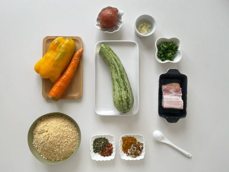 Ingredientes organizados na bancada com legumes picados e temperos separados.
