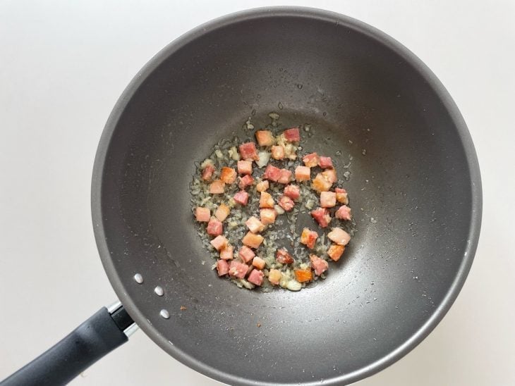 Bacon sendo frito na frigideira até dourar.