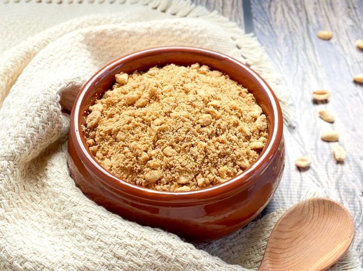 Um recipiente contendo farofa de amendoim crocante.