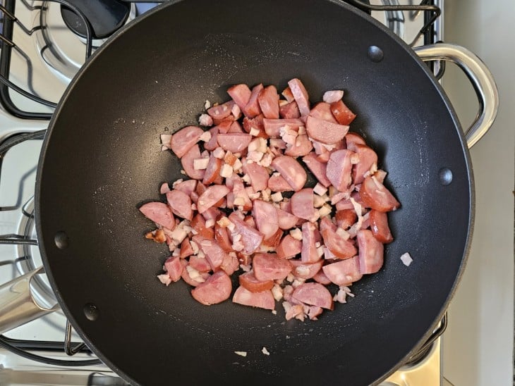 Uma frigideira com bacon e calabresa.