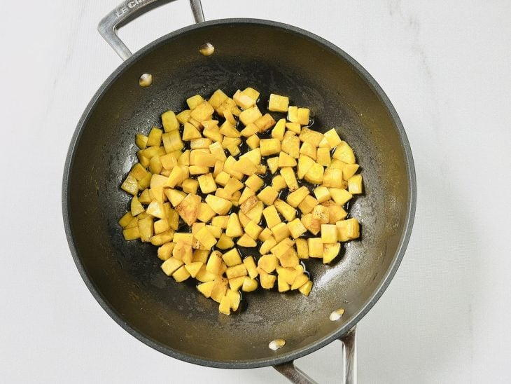 Manteiga e bananas picadas em uma frigideira grande.
