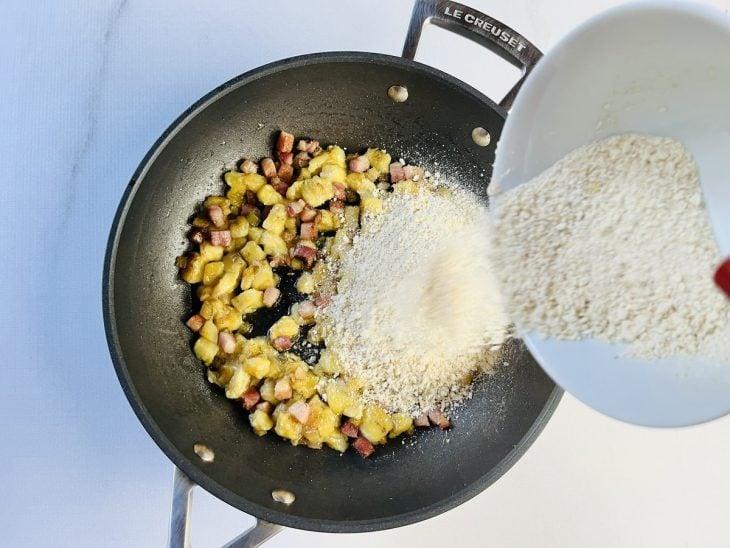 Farinha de mandioca e temperos adicionados na frigideira.