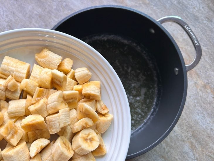 Uma panela com azeite e a manteiga derretida, e a adição de bananas.