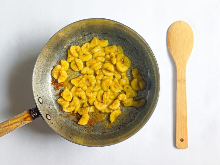 Bananas picadas grelhando em uma panela com azeite.