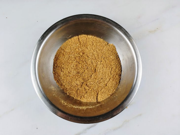 Manteiga e farinha de mandioca misturados em um recipiente de alumínio.
