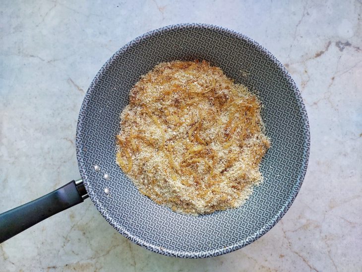 Farofa panko adicionada às cebolas na frigideira.