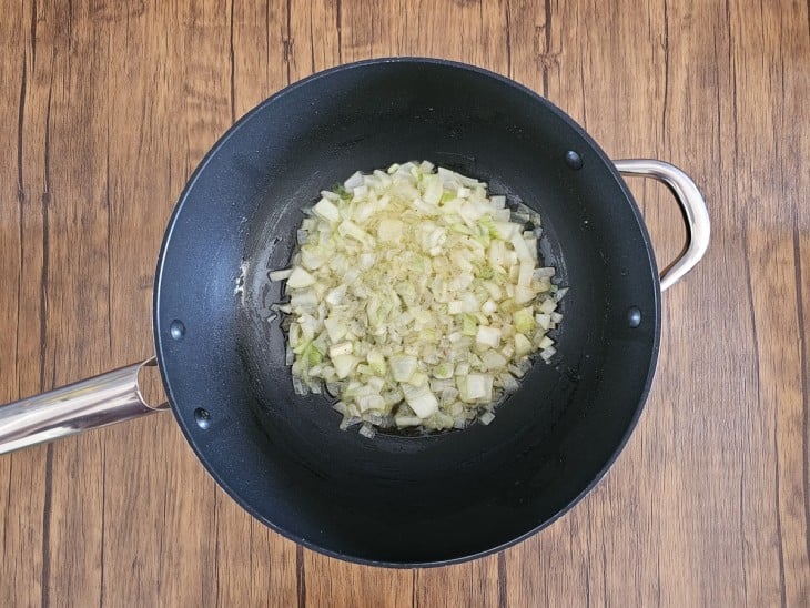 Uma frigideira com cebola sendo refogada.