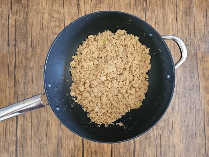 Uma frigideira com farinha de mandioca e cebola sendo refogada.