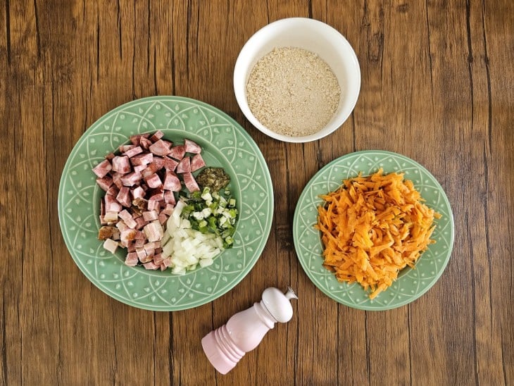 Todos os ingredientes da receita reunidos em recipientes: farinha, cenoura, bacon, calabresa, cebola e temperos.