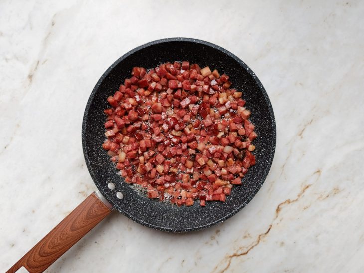 Bacon e calabresas fritos na frigideira.