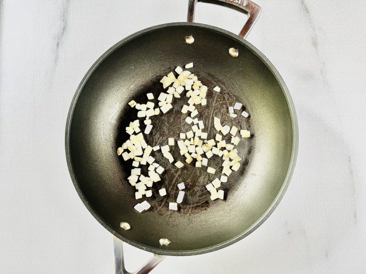 Cebola refogada no azeite numa panela.