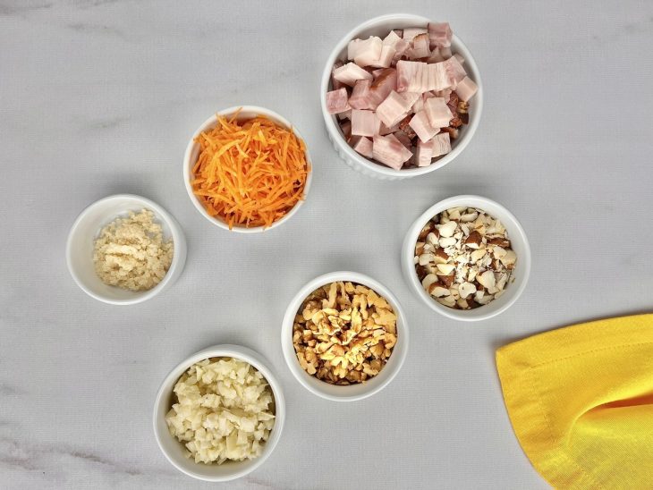 Uma bancada com vários recipientes contendo alguns ingredientes picados e ralados.