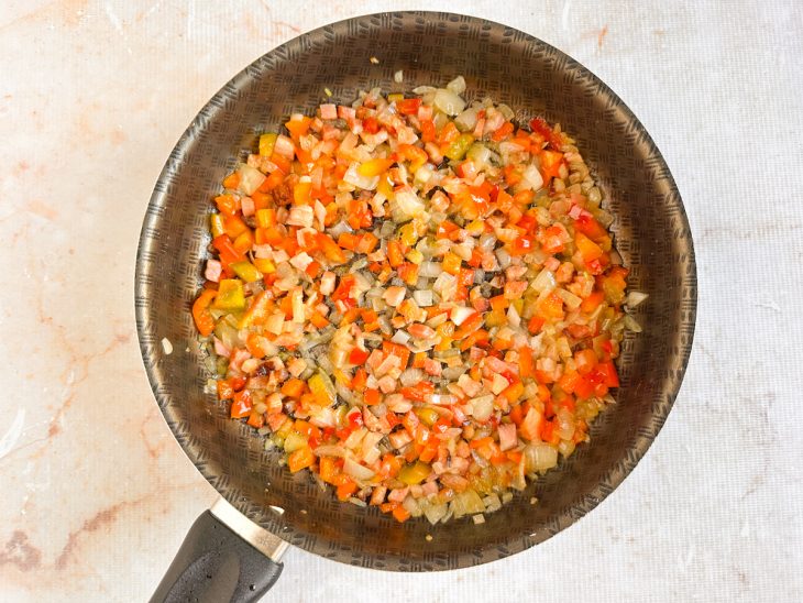 Na frigideira, pimentão a cebola adicionados.