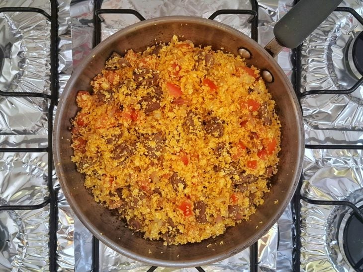 Uma panela com o coração, a cebola, o alho, a manteiga, tomate, a farinha de milho, sal e pimenta ao fogo.