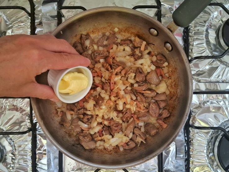 Uma panela com o coração, a cebola, o alho e a manteiga ao fogo.
