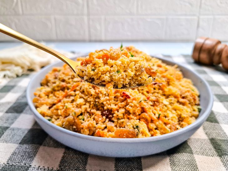 Farofa pronta, servida em prato, colher tirando uma porção.