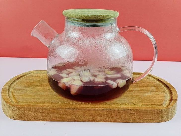 Água, suco de uva, maçã e gengibre fervidos em um recipiente.