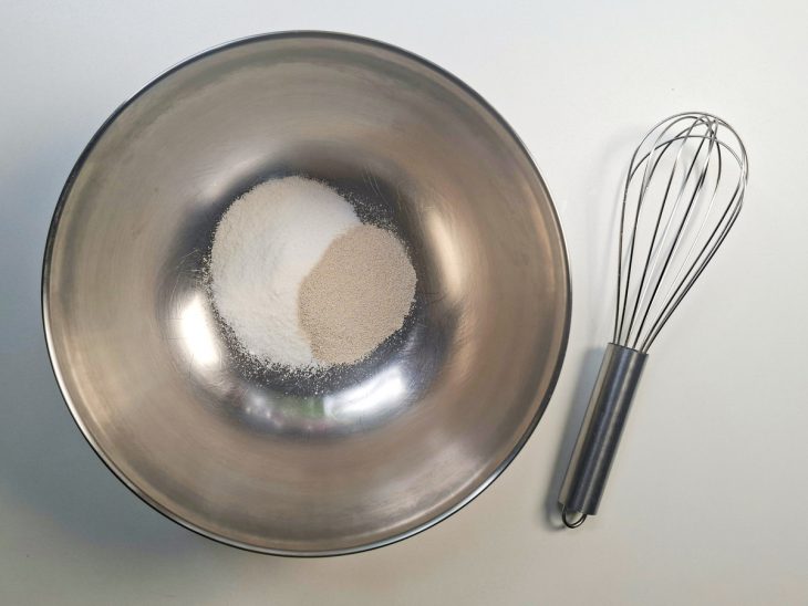 Açúcar sendo misturado ao fermento em tigela grande.